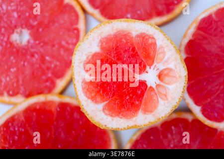 Freshly cut grapefruit slices isolated on a white background, bright pink or red citrus fruit pieces with juicy texture, healthy natural food concept. Stock Photo