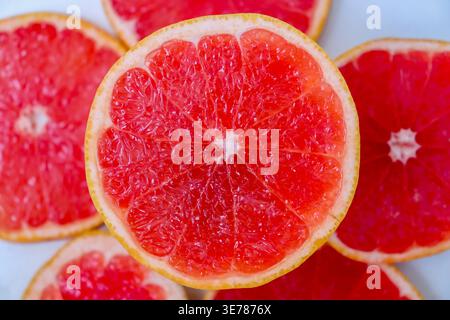 Freshly cut grapefruit slices isolated on a white background, bright pink or red citrus fruit pieces with juicy texture, healthy natural food concept. Stock Photo