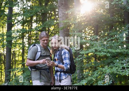 Young couple checking smartphone map together in forest Stock Photo