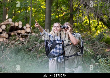 Couple observing nature with binoculars pointing into forest Stock Photo