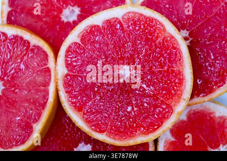 Freshly cut grapefruit slices isolated on a white background, bright pink or red citrus fruit pieces with juicy texture, healthy natural food concept. Stock Photo