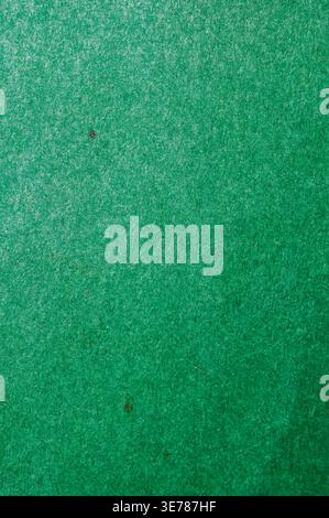 A detailed view of a vibrant green felt material, showcasing its woven texture and small natural inclusions Stock Photo