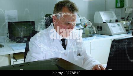 Analyzing senior scientist in white lab coat and tie checking diagnostics at lab desk with laptop Stock Photo