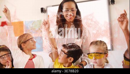 Guiding teacher wearing white blouse instructing students in classroom, safety goggles, whiteboard Stock Photo