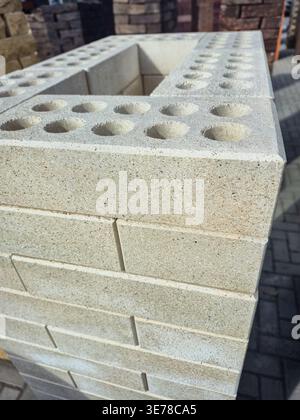 close up view of pale beige hollow bricks stacked outdoors, showcasing their textured surface and uniform circular holes Stock Photo