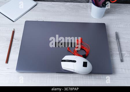 Workspace with laptop, mouse, and headphones on desk during daytime in a home office setting Stock Photo