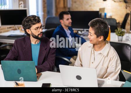 Multi ethnic team collaborating on project using laptops in modern office Stock Photo