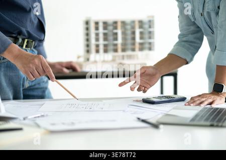 Architect or engineer in brainstorm meeting is pointing out design details and looking at design progress to advance the project. Stock Photo