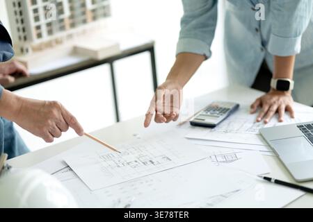 Architect or engineer in brainstorm meeting is pointing out design details and looking at design progress to advance the project. Stock Photo