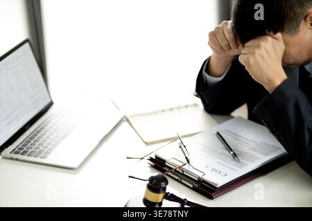 lawyer is stressed while sitting at a desk at a law firm giving the appearance of being very serious about his work and possibly having a headache fro Stock Photo