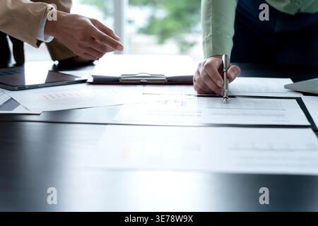 In Marketing brainstrom meeting The team is standing and pointing at the marketing plan from which data has been collected to be used as information g Stock Photo