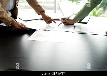 In Marketing brainstrom meeting The team is standing and pointing at the marketing plan from which data has been collected to be used as information g Stock Photo