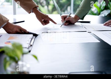 In Marketing brainstrom meeting The team is standing and pointing at the marketing plan from which data has been collected to be used as information g Stock Photo
