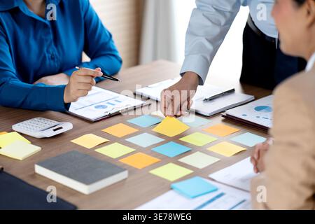 The marketing team is gathering information and writing down options and putting them on the conference table staff are helping each other make choice Stock Photo
