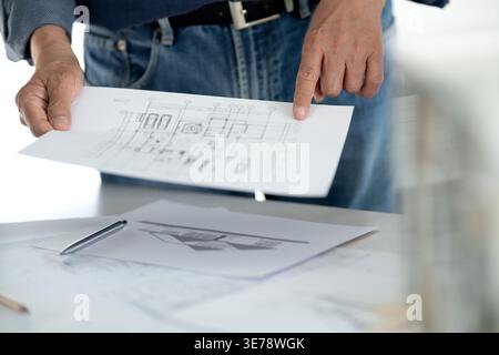 Engineers and architects are looking at the plans of the construction project consulting to plan the work and revising the construction plans to suit Stock Photo