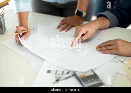 Engineers and architects are looking at the plans of the construction project consulting to plan the work and revising the construction plans to suit Stock Photo