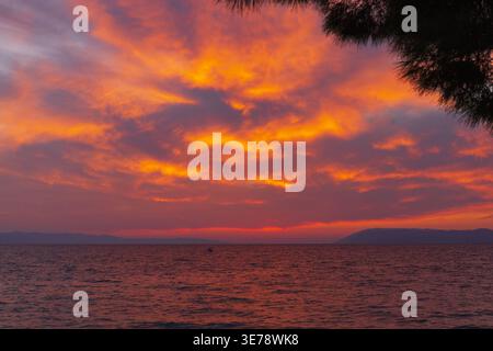 Dramatic colorful sunset sky over Adriatic sea with intense orange and red clouds. Stock Photo