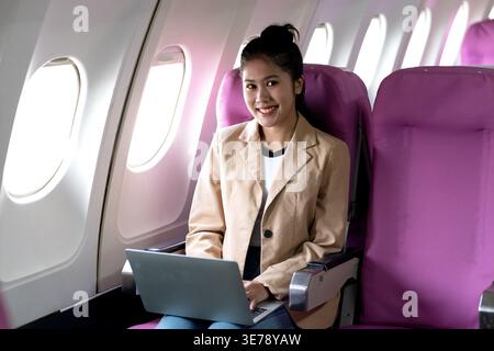 young businesswoman uses laptop while flying airplane for work and business and personal communications Stock Photo