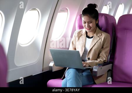 young businesswoman uses laptop while flying airplane for work and business and personal communications Stock Photo