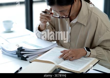 senior businesswoman Grabbing glasses to look at documents Check information meticulously and diligently in your work. Stock Photo