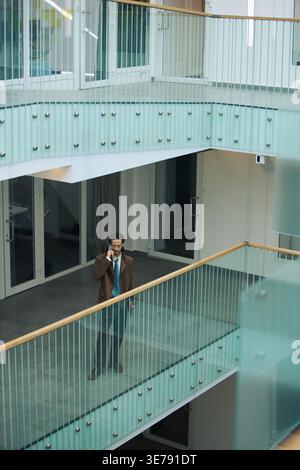 Middle Aged Businessman Talking on Smartphone in Office Atrium Stock Photo