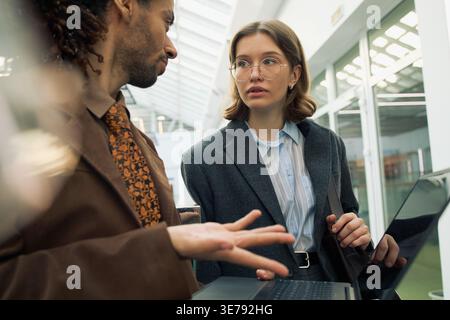 Businessman and Adult Woman Discussing Project on Laptop Stock Photo