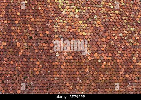 Weathered terracotta roof tiles on a traditional Swiss house showing aged texture, moss, and lichen. Ideal for architectural backgrounds and rustic de Stock Photo