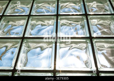 Low angle view of glass block ceiling reflecting bright sunlight and blue sky in a geometric grid Stock Photo