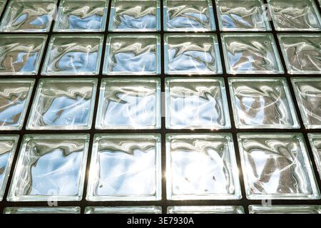 Low angle view of glass block ceiling reflecting bright sunlight and blue sky in a geometric grid Stock Photo