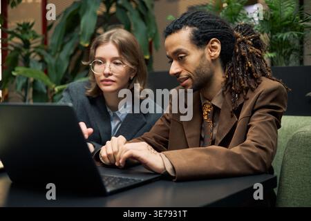 Businesswoman and Man Analyzing Laptop Data for Team Strategy Stock Photo