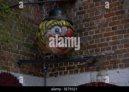 Merksem, Antwerp, Belgium, March 19, 2026: Grotesque clown head decoration mounted on a brick wall of a building. Unusual urban detail reflecting loca Stock Photo