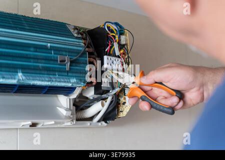 A male air conditioner technician or air conditioning installation. technician is about to repair air conditioning in homes and buildings. Stock Photo