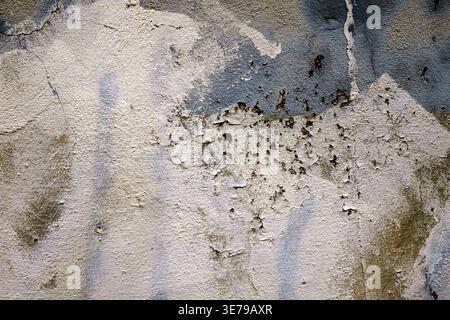 Close up of a distressed concrete surface with remnants of white and blue paint. Stock Photo