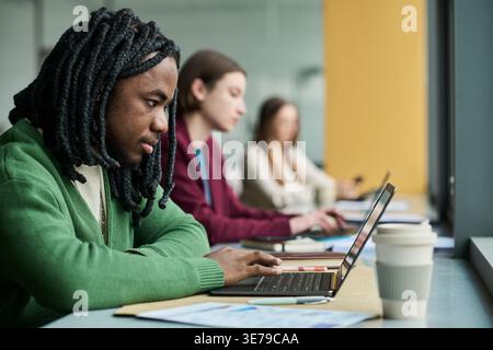 Black Man Typing on Laptop during Focused Office Work Session Stock Photo