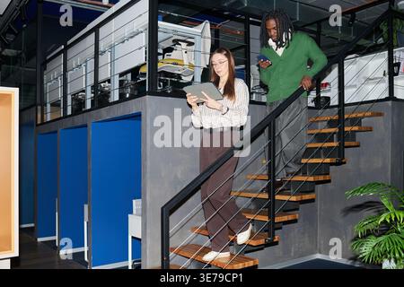 Business Colleagues Descending Stairs While Using Mobile Devices Stock Photo