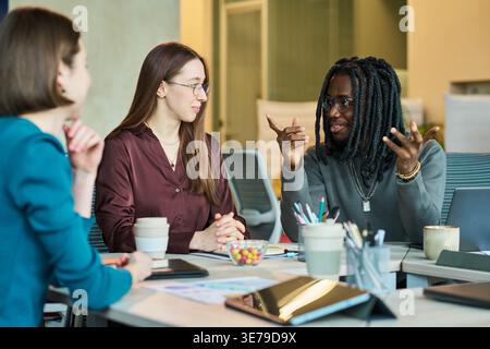 Black Man Leading Team Discussion during Creative Office Meeting Stock Photo