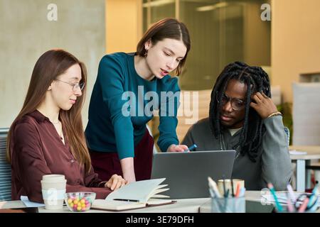 Diverse Coworkers Collaborating on Laptop in Office Meeting Stock Photo