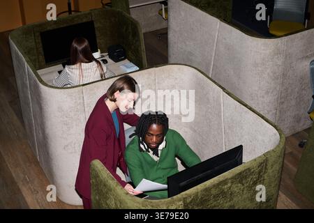 Black Man and Adult Woman Reviewing Documents in Office Booth Stock Photo