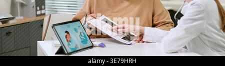 Header of Middle Aged Woman Reviewing Medical Results with Doctor in Clinic Stock Photo