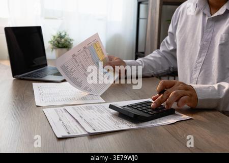 Business professional reviewing financial documents and calculating numbers with calculator, analyzing reports, budgeting expenses, tax preparation an Stock Photo