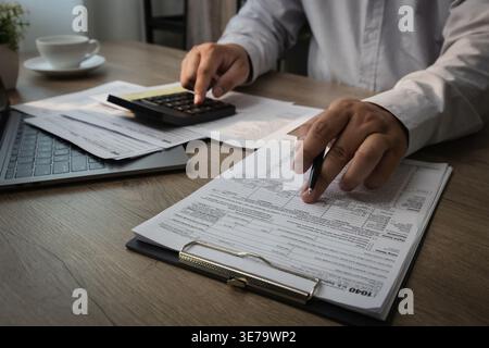 Hands using calculator on expense report document with pen performing financial calculation and reviewing budget data for accounting analysis and expe Stock Photo