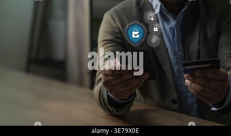 Hand holding smartphone and credit card performing mobile payment process with digital security icons showing authentication, verification, transactio Stock Photo
