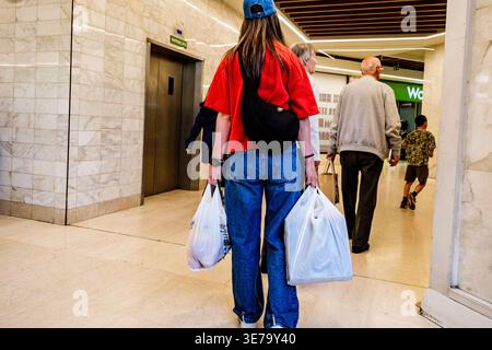 Epsom London UK, April 09 2026, Young Woman Wearing a Red Top And Blue Denim Jeans Carrying Shopping Bags in Both Hands Stock Photo