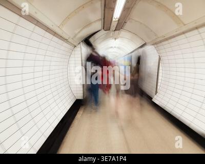 Passenger transit tunnel at London Kings Cross Charing Cross underground station station with blurred figures in motion. Stock Photo