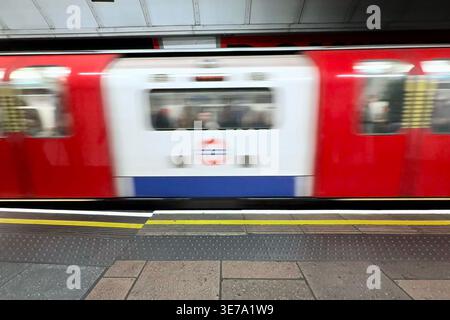 Patform at London Kings Cross underground station with blurred train pulling into platform. Stock Photo