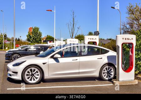 Line of Tesla Supercharger EV charging stations in the car parking area of the Lidl supermarket - Chatellerault, Vienne (86), France. Stock Photo