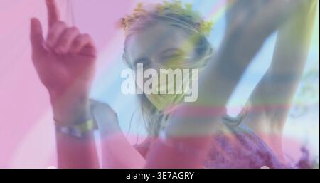 Dancing blonde woman wearing floral crown and sleeveless top at outdoor festival, wristband visible Stock Photo