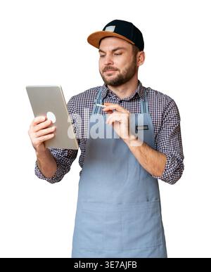 Isolated male entrepreneur in cap and apron using digital tablet and stylus. Stock Photo