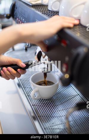 Chinese female barista making coffee using machine in coffee shop Stock Photo