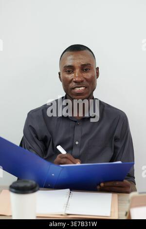 Close-up shot Black man smiling while holding folder and pen in the office Stock Photo